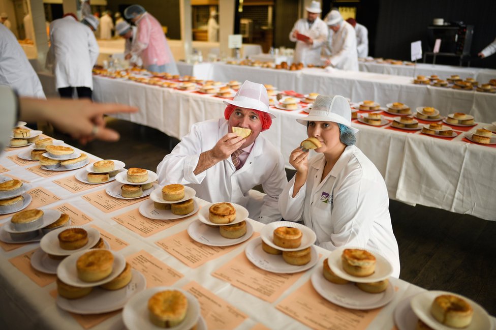 Judges hold up pies to their faces.