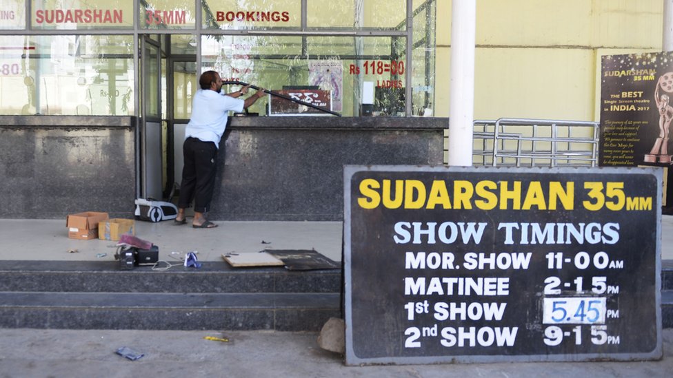 An Indian worker cleans a booking counter at a cinema theatre in Hyderabad on March 2, 2018.