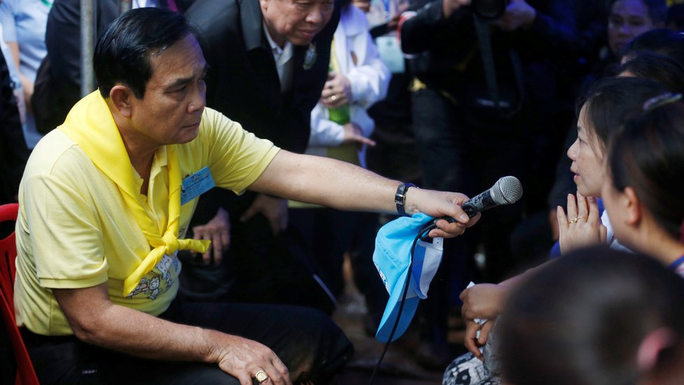 The prime minister holds microphone for relative as he listens to her at an event