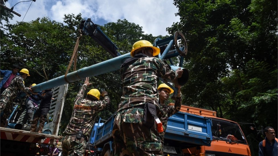 Technicians lifting water pumps at drilling site near the cave system