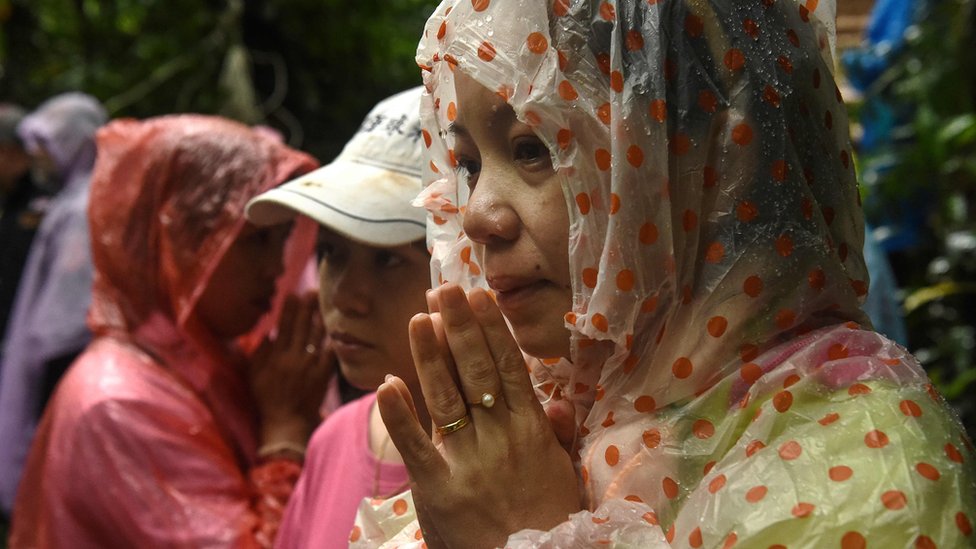 A woman is pictured praying in waterproof hood outside of site