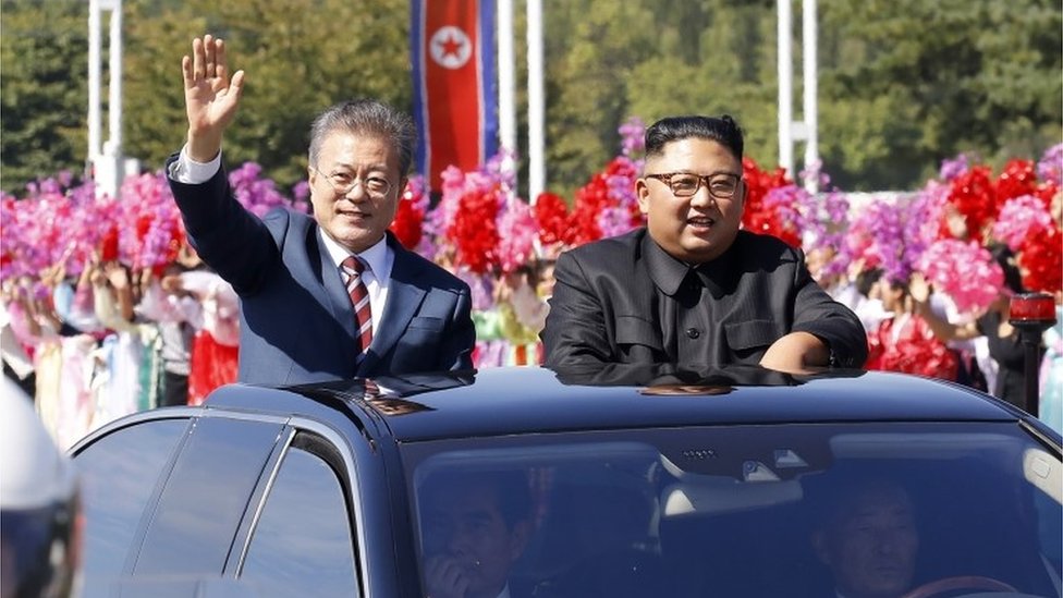 Moon Jae-in (left) and Kim Jong-un wave from an open top car in Pyongyang