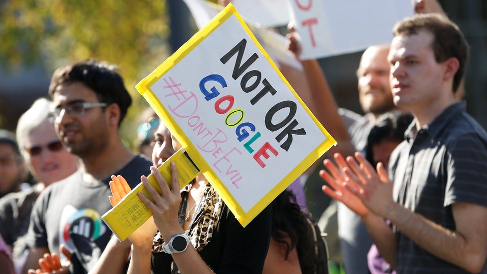 A Google employee (centre) holds a sign that reads 