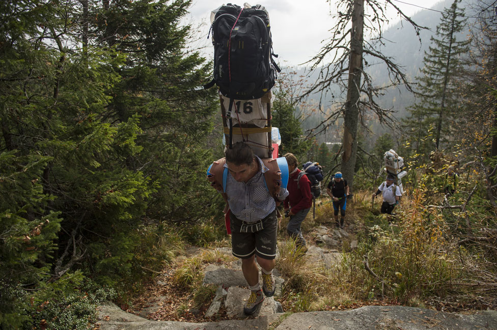 A man walks up a mountain carrying suitcases