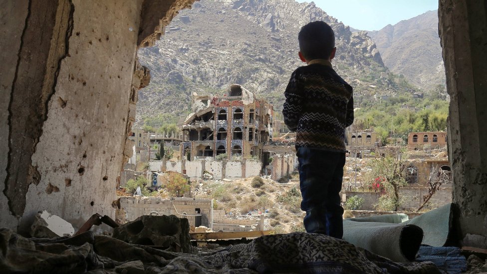 A photo taken on March 18, 2018, shows a Yemeni child looking out at buildings that were damaged in an air strike in the southern Yemeni city of Taez