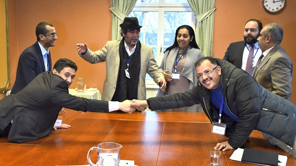 Houthi delegate Abdelqader Mourtada (L) and government delegate Brigadier General Asker Zaeel shake hands at the negotiating table in Stockholm, 13 December