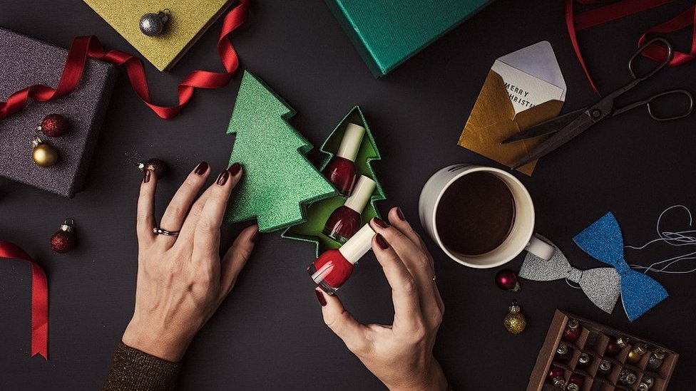 Woman packing nail polish into a pretty gift-box, shaped like a glittery Christmas Tree