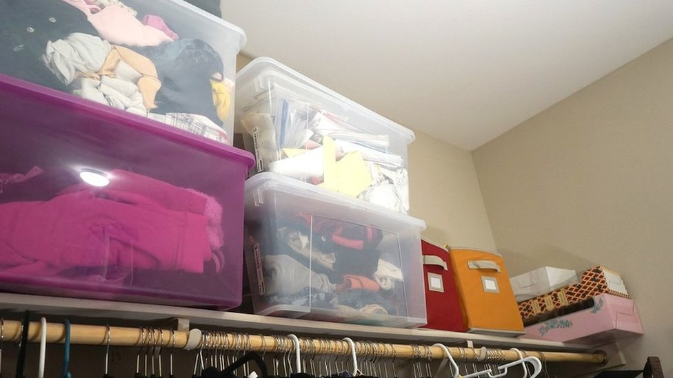 Shot of a closet, with clothes hanging on the rail and boxes piled up high on the shelves