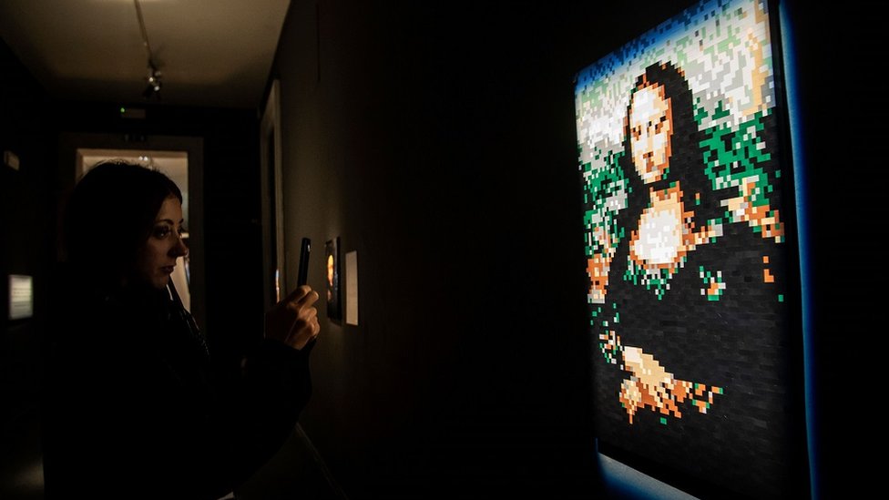 A visitor takes a picture of a sculpture of 'Mona Lisa' made with Lego bricks.