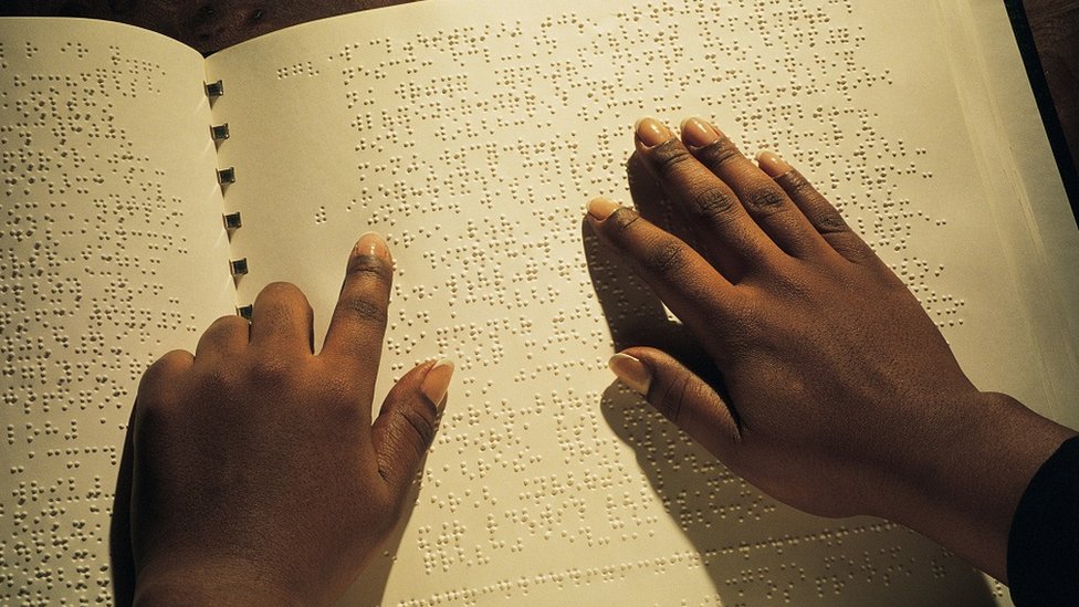 Hands reading Braille book