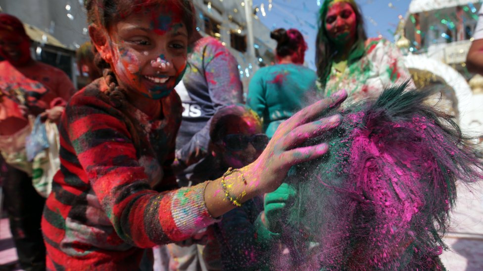 A child rubs colour onto another child's head