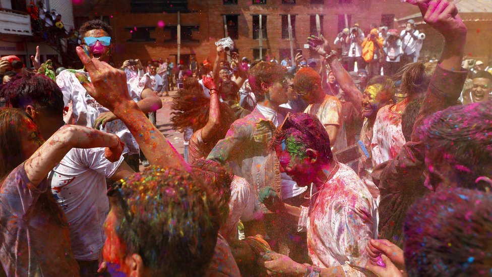 Nepalese people painted with coloured powder dance in Kathmandu