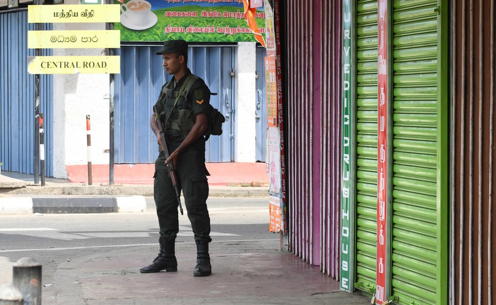 A Sri Lankan soldier stands guard next to closed shops in Batticaloa