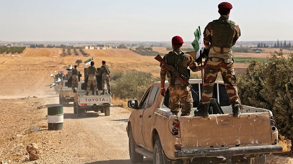 Syrian National Army fighters travelling in trucks