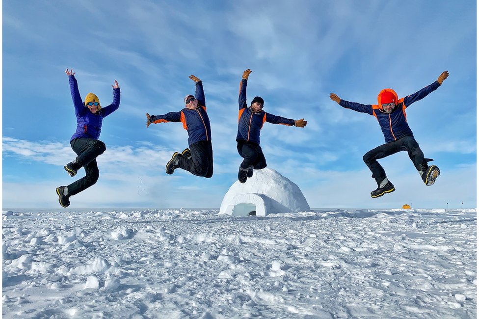 Justin Rowlatt (right) jumping with colleagues and a scientist in Antarctica