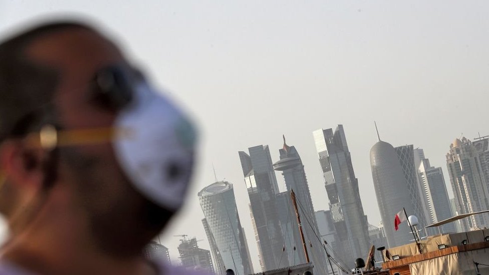 Man wearing a facemask with the Doha skyline in the background