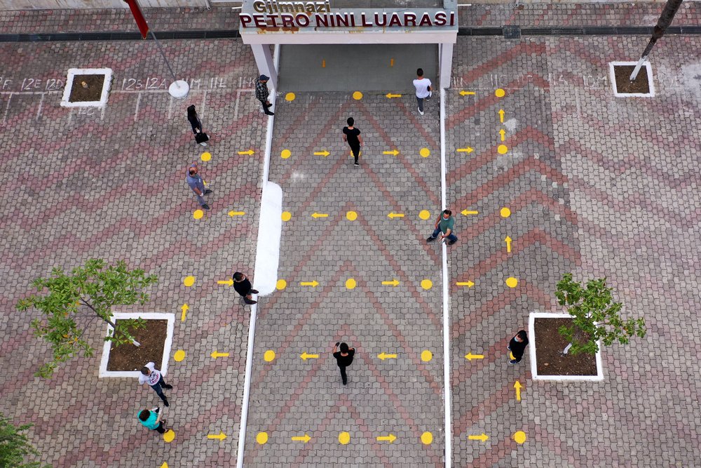 High school students in Albania follow the directions on the ground to enter their building whilst maintaining social distancing