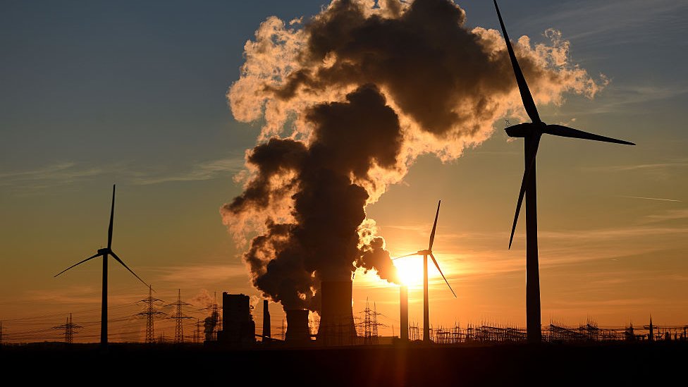 Electricity pylons and wind turbines stand beside a coal-fired power plant in Germany