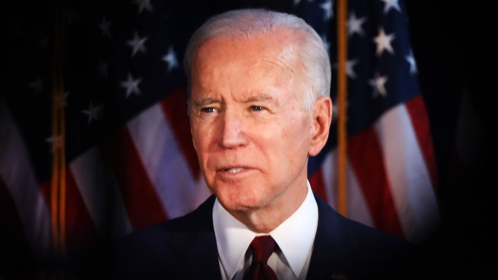 Joe Biden in front of US flags.