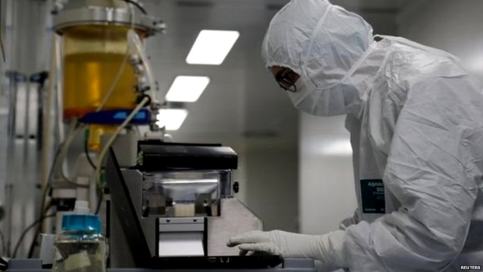 Scientist with full protection gear examining a sample