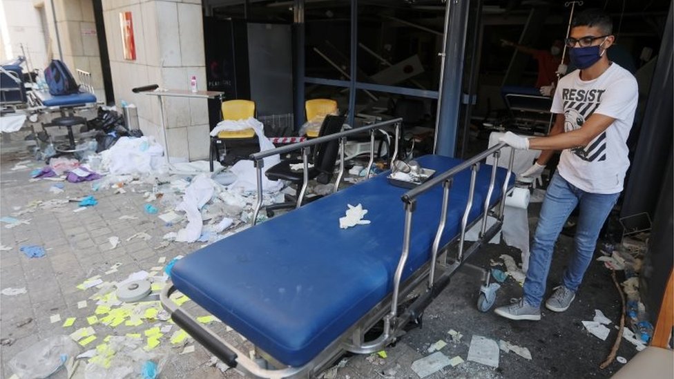 A man wearing a face mask moves a gurney at a damaged hospital following Tuesday