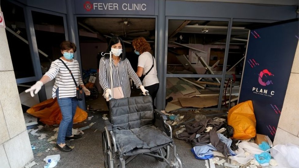 A woman wearing a face mask pushes a wheelchair at a damaged hospital following Tuesday