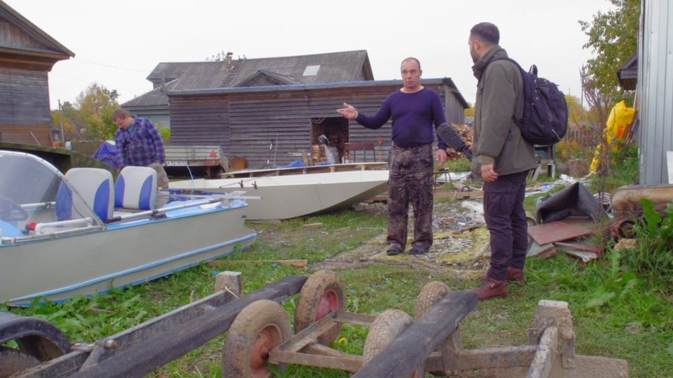 A man talks to a reporter in a boatyard