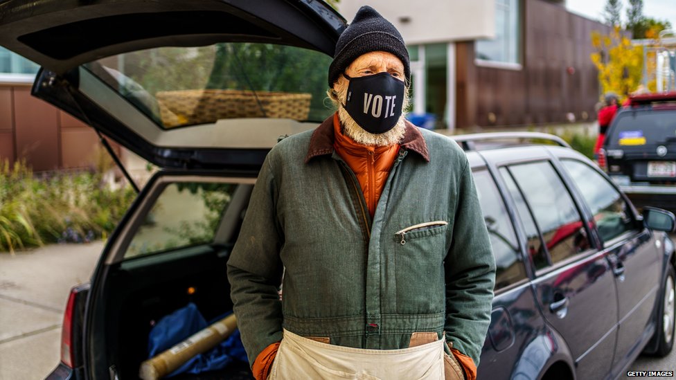 Apple vendor Rikardo Jahnke wears a facemask reading 