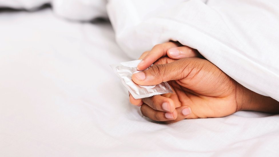 The hands of a young couple holding a condom (stock photo)
