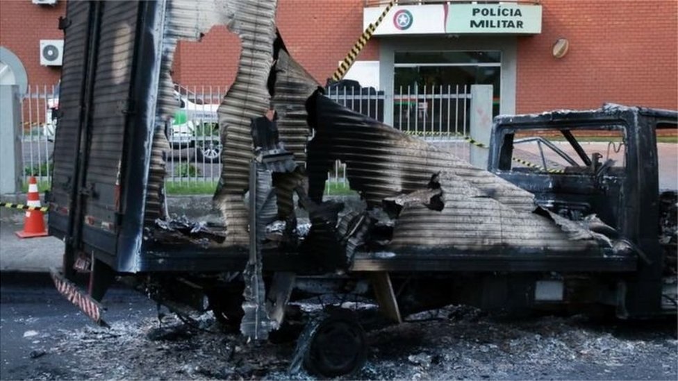 The charred remains of a truck at the gates of the state military police headquarters in Criciuma