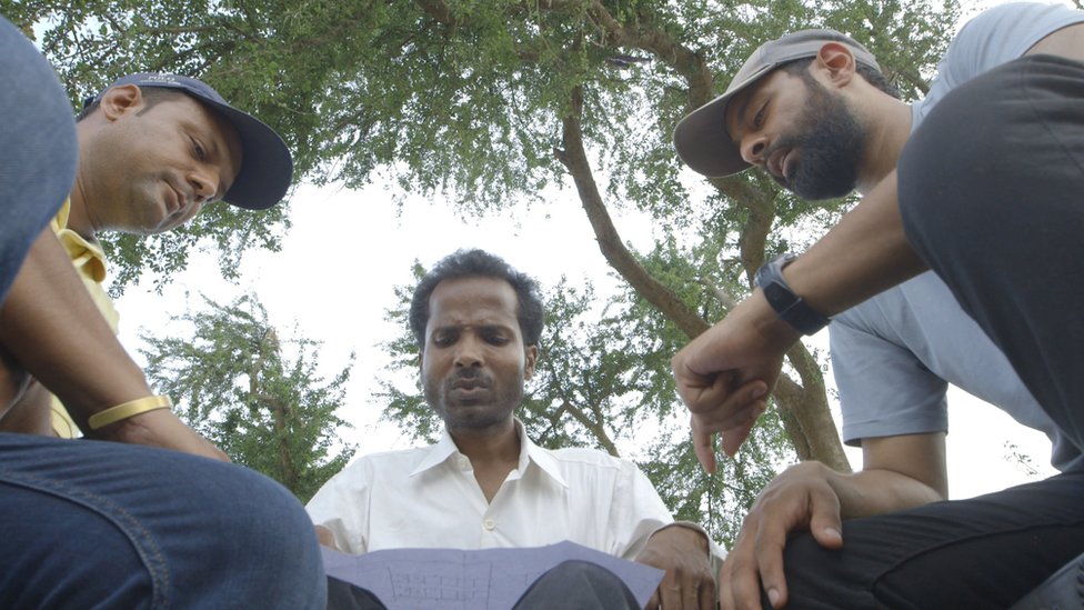 The three founders looking at plans for a facility