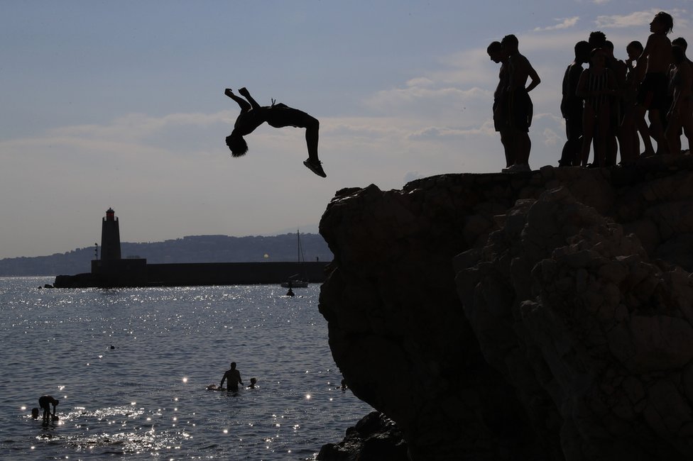 Young men leap off rocks into the Meditteranean Sea at Nice, south-eastern France