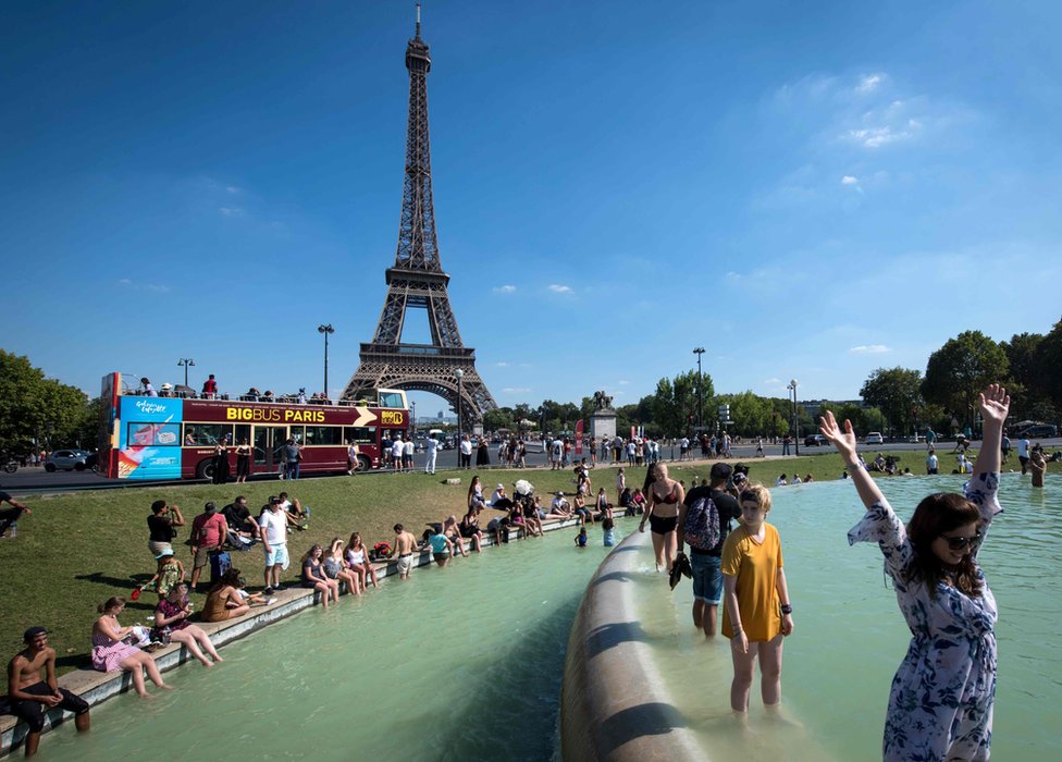 People cool themselves at the Trocadero Fountain in front of The Eiffel Tower in Paris