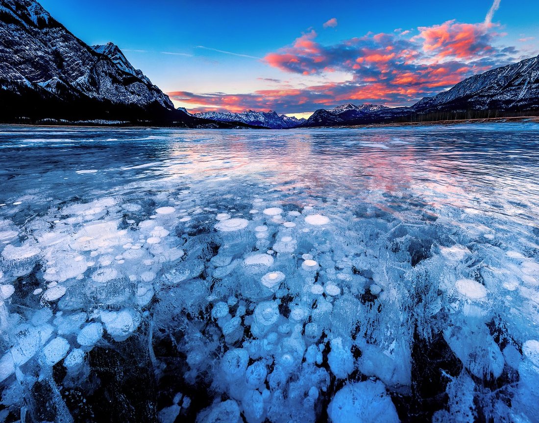 Burning sky and the panoramic view of the frozen Abraham Lake, Alberta, Canada at sunset. Stacks of bubbles trapped inside the lake look amazing.
