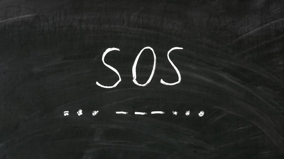 A blackboard with the letters SOS and the SOS message written in Morse code