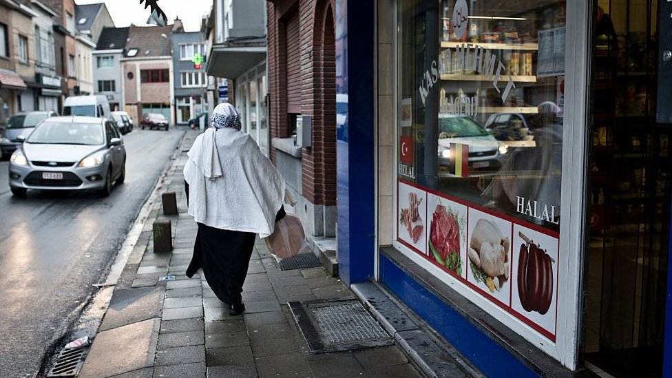 A Muslim woman walks past halal shops in Vilvoorde, Belgium