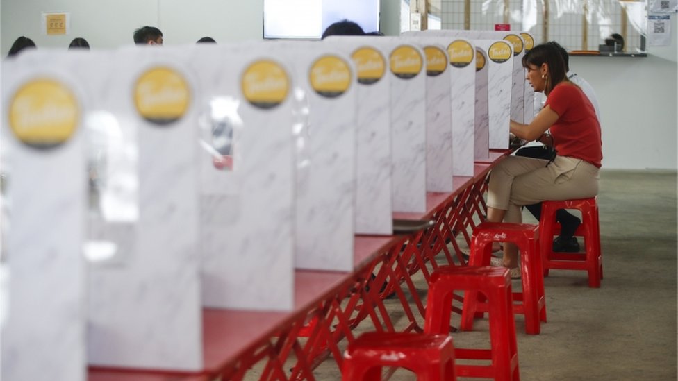 People eat lunch on tables partitioned by cardboard and plastic sheets in order to enforce social distancing in Bangkok, Thailand