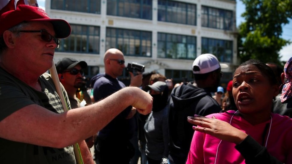 A man with a US flag argues with a woman