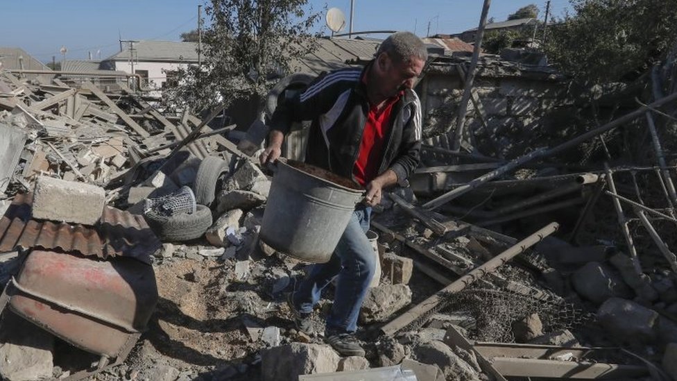 A man removes debris from shelling in the Nagorno-Karabakh capital, Stepanakert