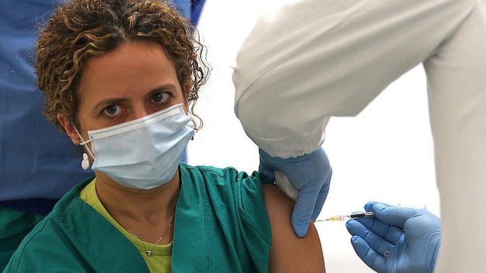 A nurse inoculates a fellow health worker in Naples, Italy. 27 Dec 2020