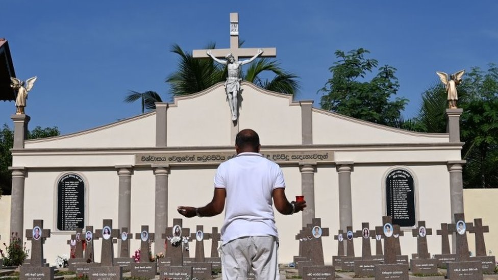 A relative pays his respects at a graveyard