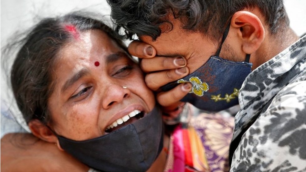 A woman mourns with her son after her husband died due to the coronavirus disease (COVID-19) outside a mortuary of a COVID-19 hospital in Ahmedabad, India, April 20, 2021