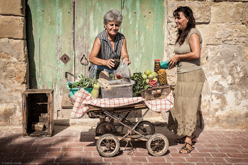 Woman bags some food for a customer at an outdoor stall