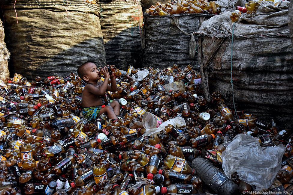 Child surrounded by plastic bottles