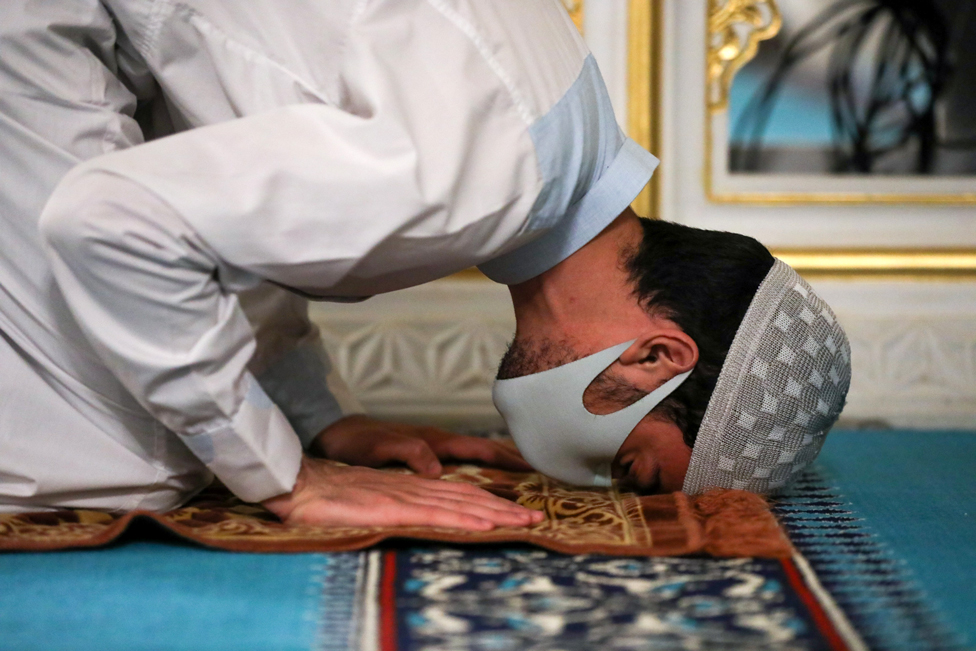 A Muslim worshipper prays whilst wearing a face mask