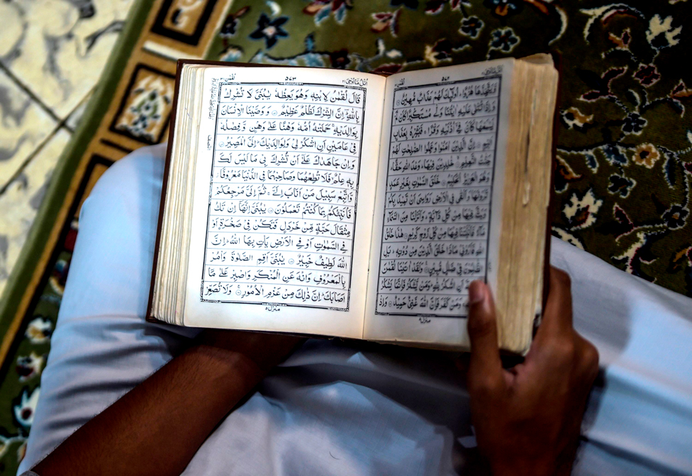 A worshipper reads the Koran at his house