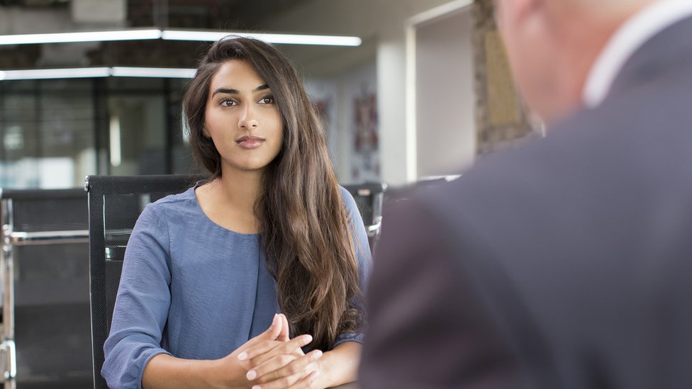 A woman sits opposite a man