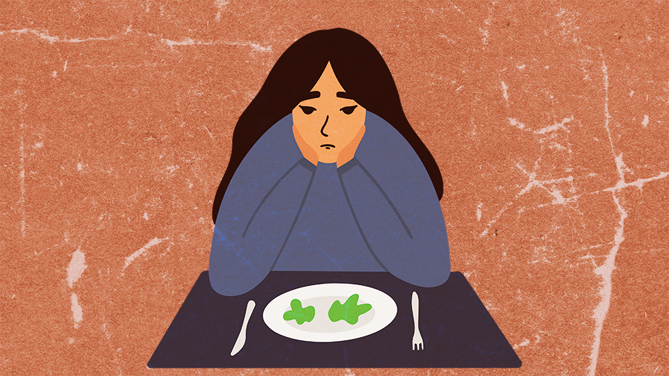 A young woman sitting at a table with a near-empty plate