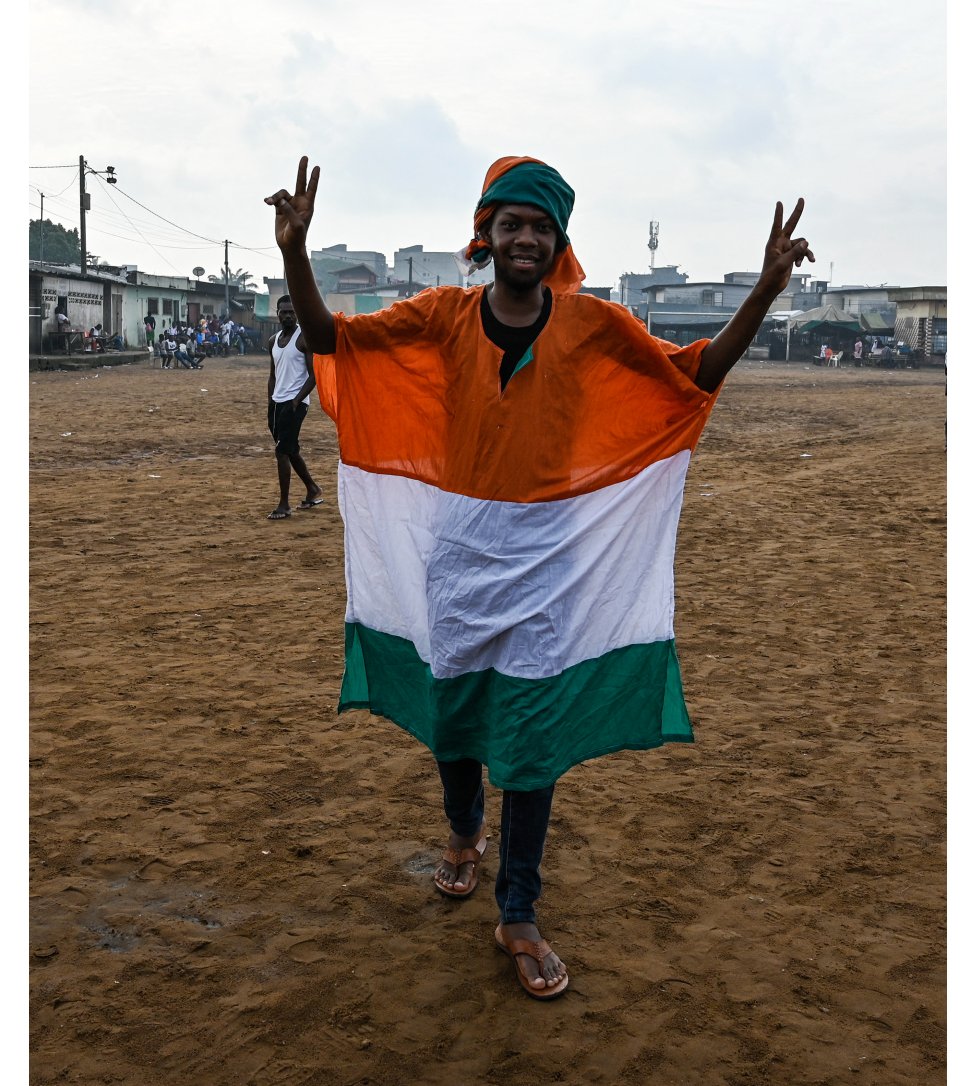 A man in an Ivorian flag making a V for victory sign