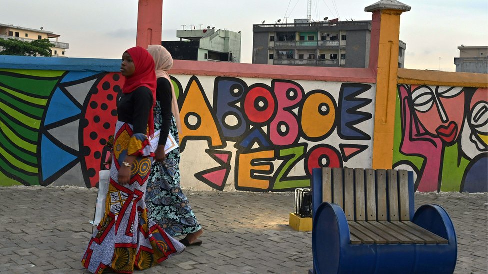 Two women walking past a mural